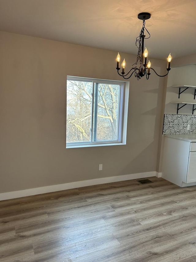 unfurnished dining area featuring a chandelier and light hardwood / wood-style floors