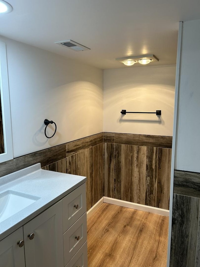 bathroom with vanity, hardwood / wood-style floors, and wooden walls