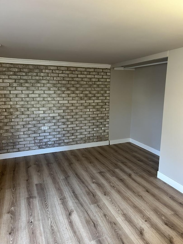 spare room featuring brick wall and hardwood / wood-style floors