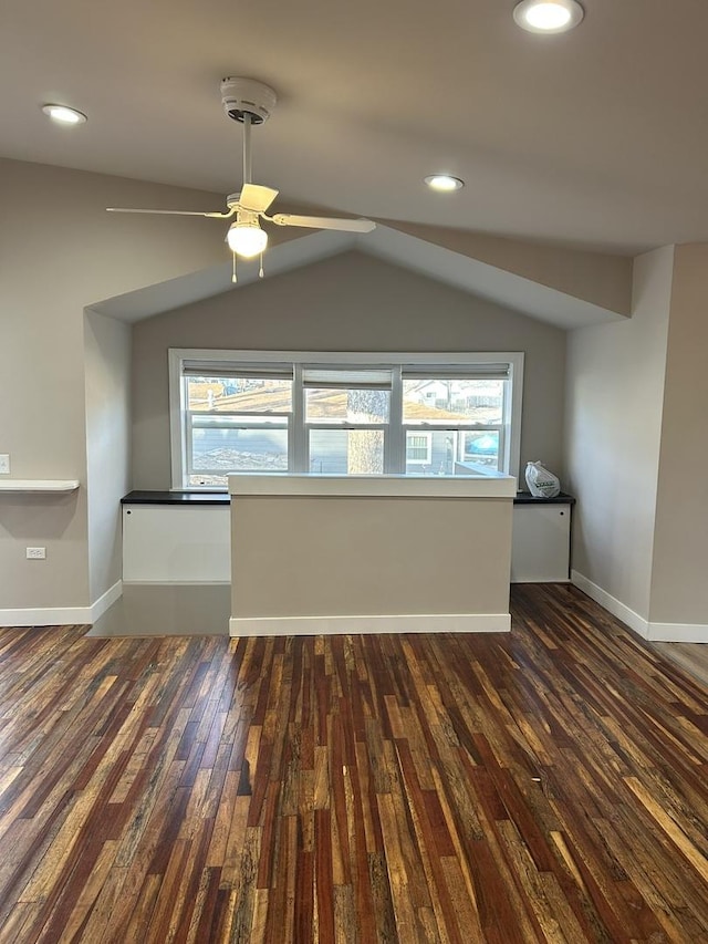 empty room featuring a wealth of natural light, vaulted ceiling, dark hardwood / wood-style floors, and ceiling fan