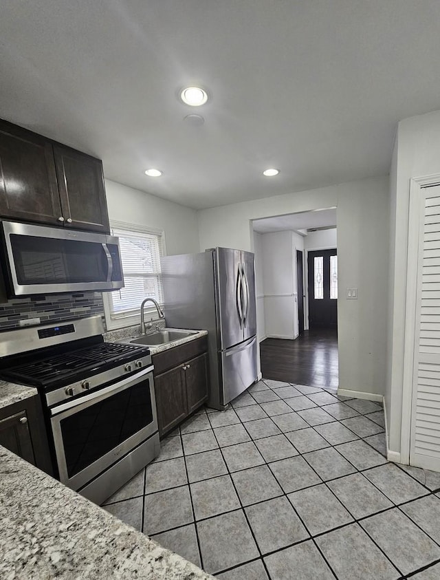 kitchen featuring stainless steel appliances, light stone countertops, and dark brown cabinets