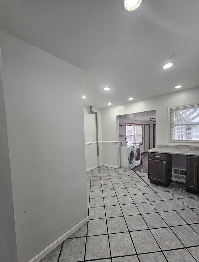 interior space featuring light tile patterned floors, washing machine and clothes dryer, and dark brown cabinetry