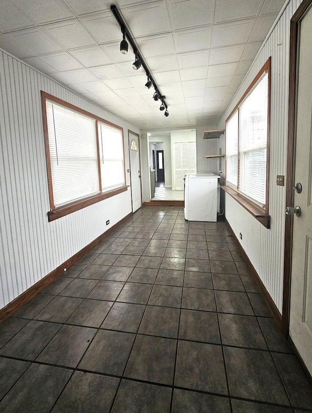 interior space featuring dark tile patterned flooring, washer / dryer, and a wealth of natural light