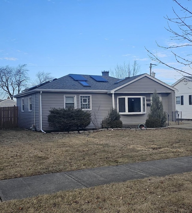 ranch-style home with a front lawn and solar panels