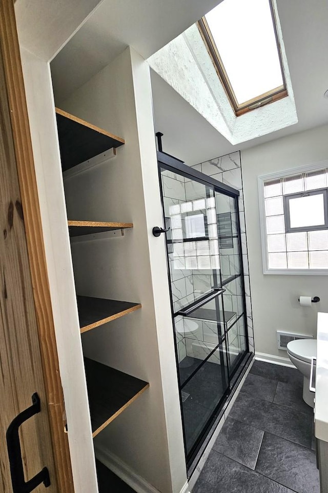 bathroom featuring toilet and a shower with door