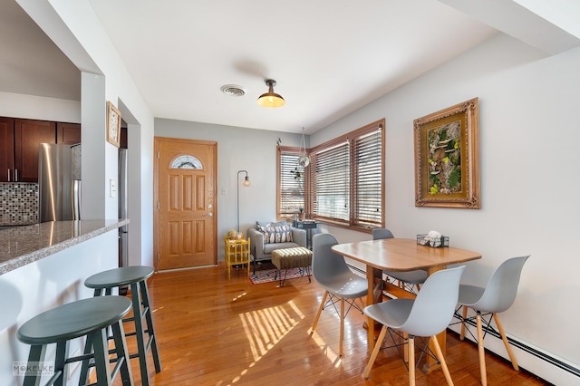 dining area featuring baseboard heating and light hardwood / wood-style floors