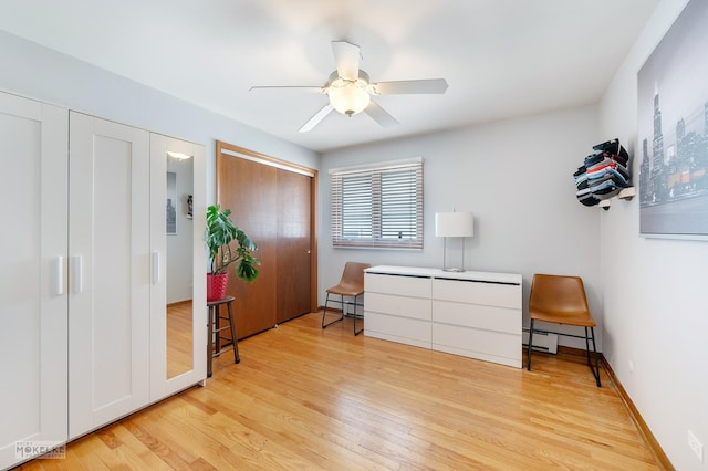 bedroom with baseboard heating, ceiling fan, multiple closets, and light hardwood / wood-style floors