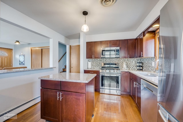 kitchen featuring pendant lighting, sink, baseboard heating, stainless steel appliances, and light hardwood / wood-style floors