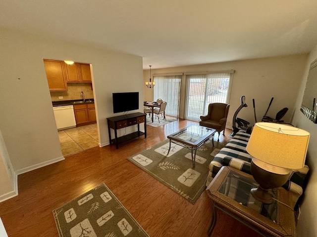 living room featuring an inviting chandelier, sink, and light hardwood / wood-style floors