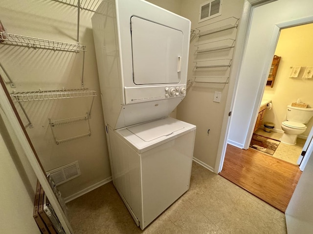 clothes washing area featuring stacked washing maching and dryer