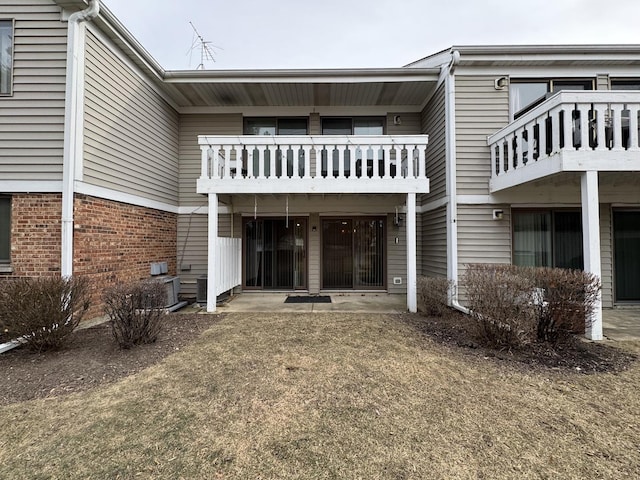 back of house featuring a balcony, a patio area, and a lawn