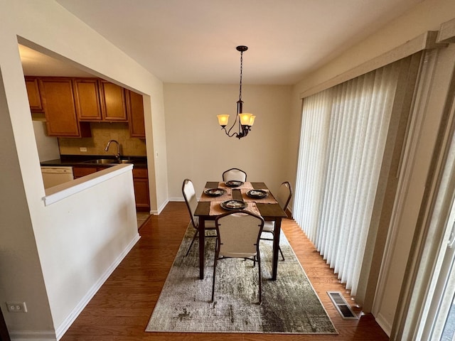 dining area with dark wood-type flooring, sink, and a notable chandelier