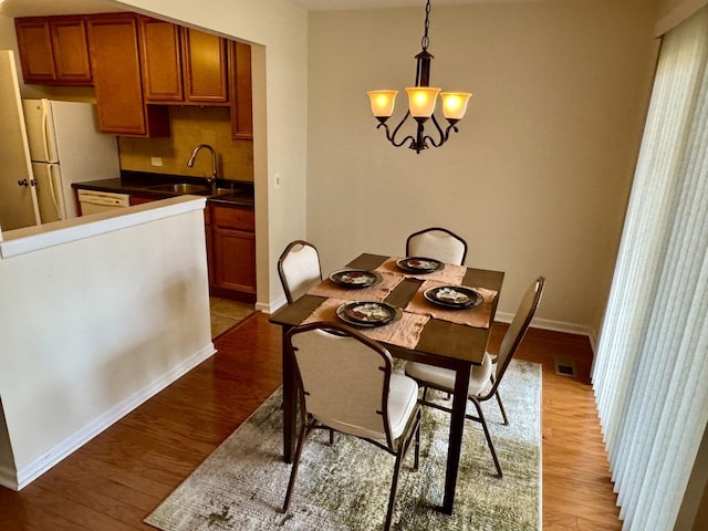 dining area with an inviting chandelier, sink, and light hardwood / wood-style flooring