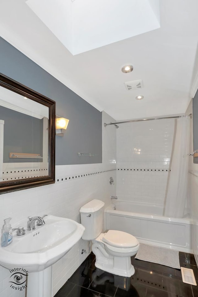 full bathroom featuring shower / bathtub combination with curtain, sink, tile walls, tile patterned floors, and toilet