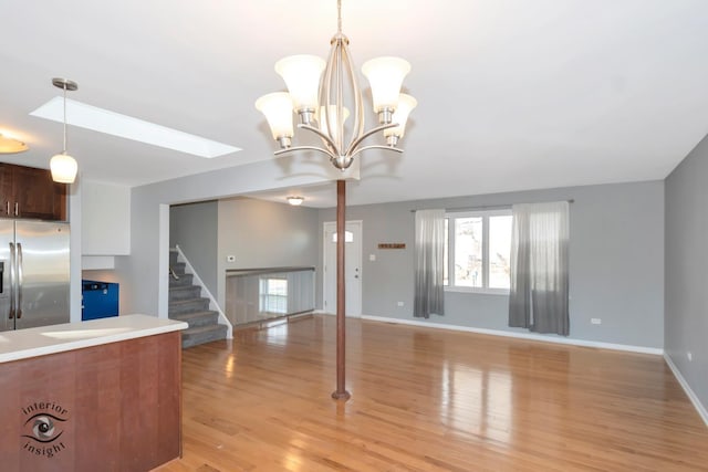 interior space featuring a skylight, light hardwood / wood-style flooring, and a chandelier