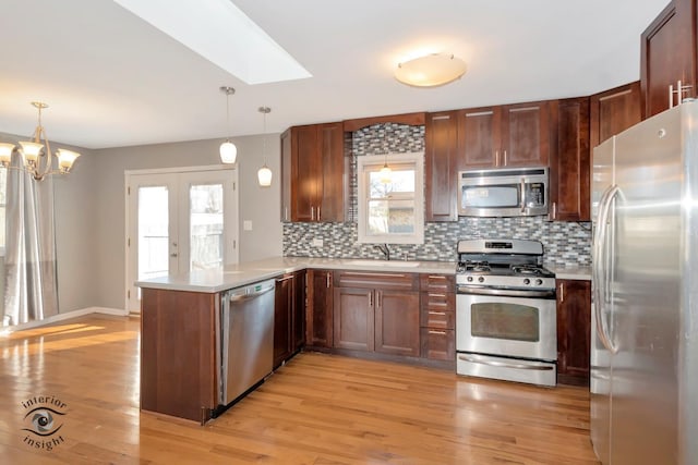 kitchen with stainless steel appliances, pendant lighting, backsplash, and kitchen peninsula