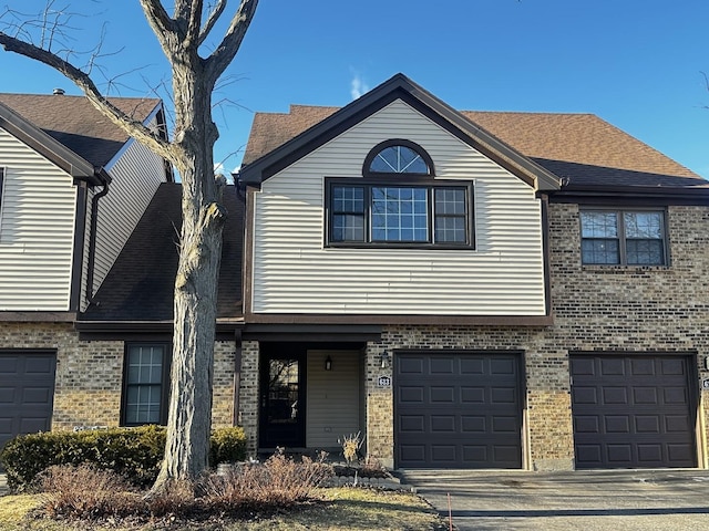 view of front of house with driveway, brick siding, and an attached garage