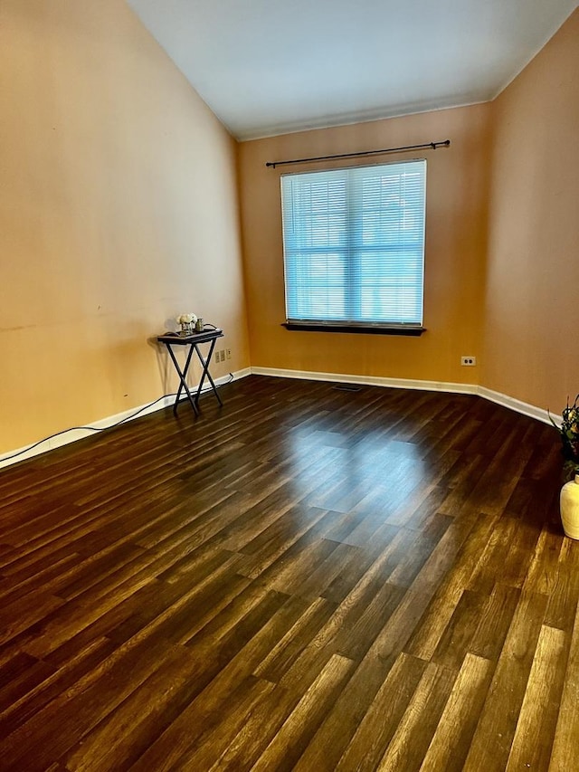 empty room featuring dark wood finished floors and baseboards