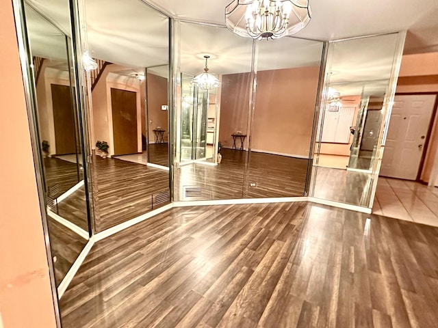 spare room with visible vents, wood finished floors, and ceiling fan with notable chandelier