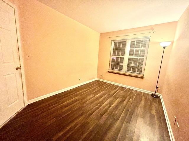 spare room with dark wood-style floors and baseboards