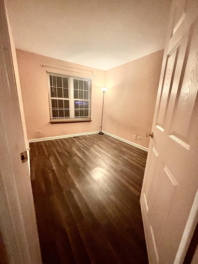 empty room with baseboards and dark wood-style flooring