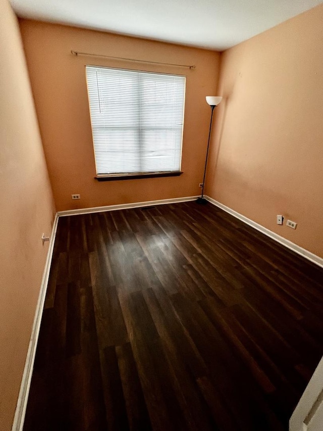 empty room featuring dark wood-style flooring and baseboards