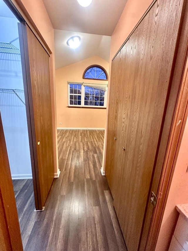 hallway with vaulted ceiling, dark wood-style floors, and baseboards