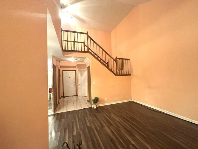 interior space with a towering ceiling, stairs, baseboards, and wood finished floors