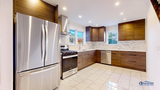 kitchen with sink, backsplash, wall chimney range hood, and appliances with stainless steel finishes