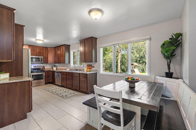 kitchen with light stone counters, stainless steel appliances, and sink