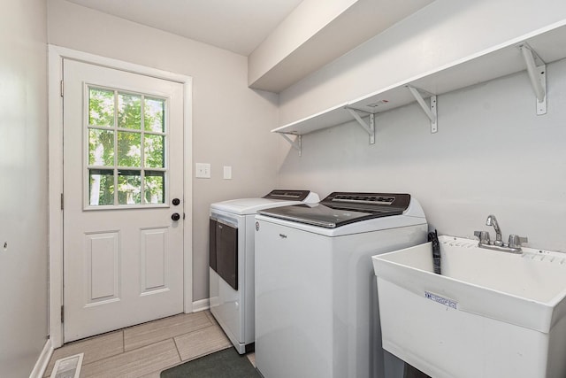 clothes washing area with sink and independent washer and dryer