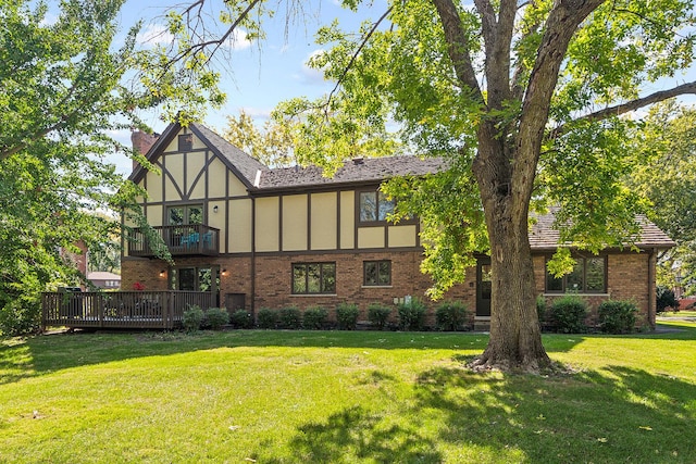 back of property featuring a balcony and a lawn