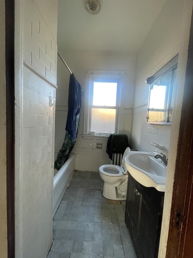 full bathroom with a healthy amount of sunlight, toilet, vanity, and tile walls