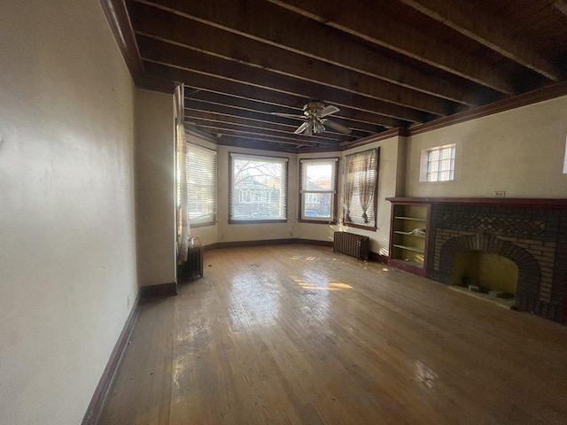 unfurnished living room featuring beamed ceiling, radiator heating unit, wood-type flooring, and a brick fireplace