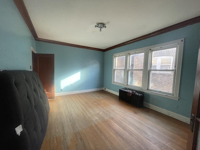 empty room featuring ornamental molding, radiator, and light wood-type flooring