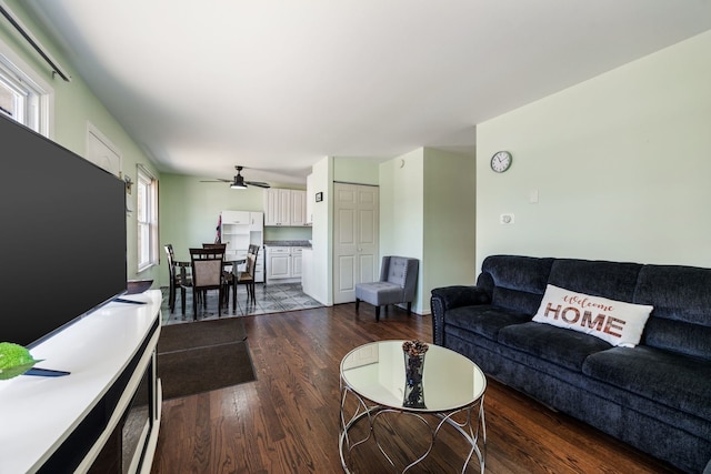 living room featuring dark wood-type flooring and ceiling fan