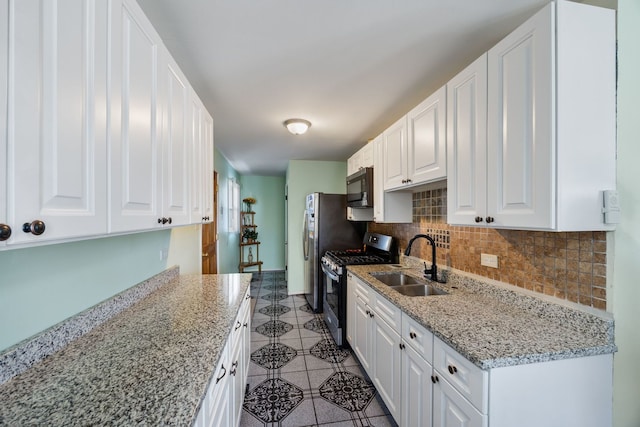 kitchen featuring light stone counters, appliances with stainless steel finishes, sink, and white cabinets