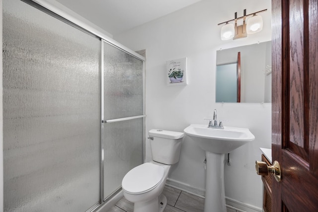 bathroom featuring tile patterned floors, toilet, and a shower with door