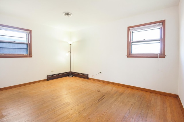 empty room featuring plenty of natural light, light hardwood / wood-style floors, and a baseboard radiator