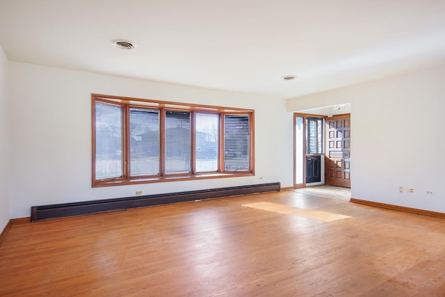 unfurnished room featuring light hardwood / wood-style flooring and a baseboard heating unit