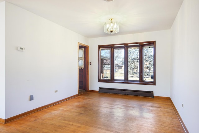 unfurnished room featuring hardwood / wood-style flooring, a baseboard radiator, and a chandelier