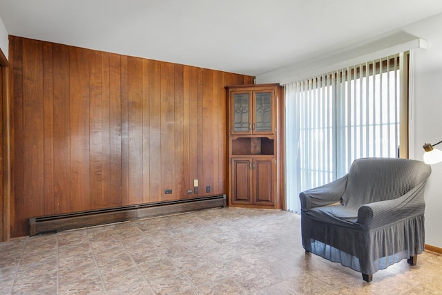 living area featuring a baseboard heating unit and wooden walls