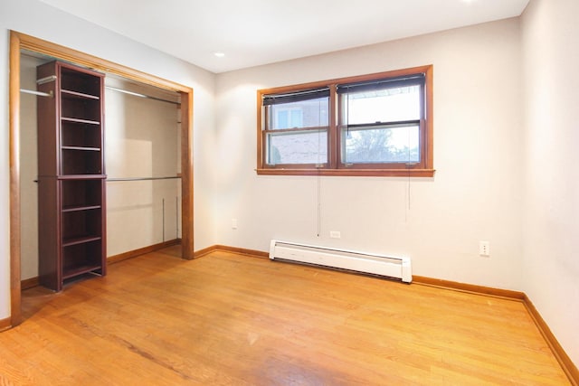 unfurnished bedroom featuring light wood-type flooring and baseboard heating