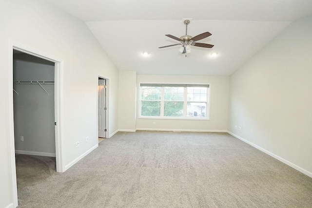 unfurnished bedroom with vaulted ceiling, a spacious closet, light carpet, and ceiling fan