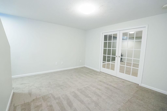 carpeted spare room featuring french doors