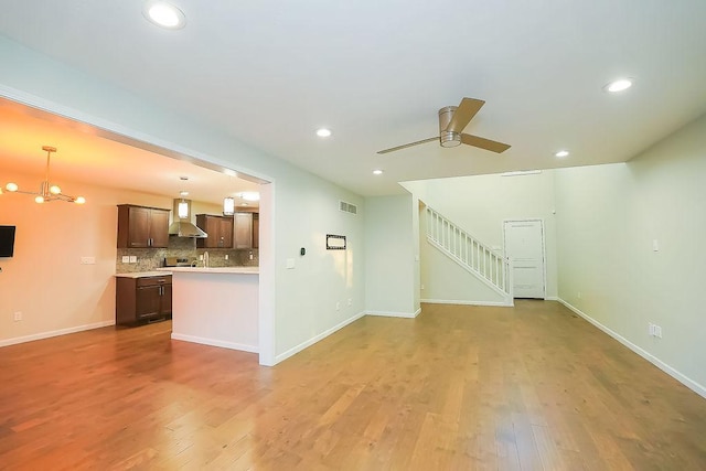 unfurnished living room with hardwood / wood-style flooring and ceiling fan with notable chandelier