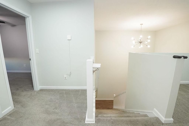 stairway with an inviting chandelier and carpet floors