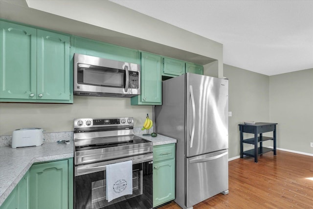 kitchen with light wood-type flooring, stainless steel appliances, and green cabinets