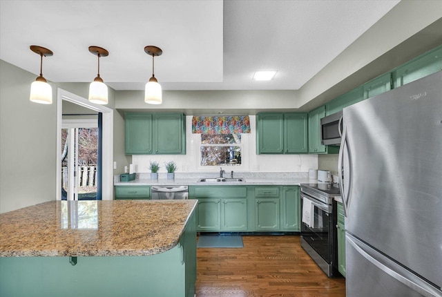 kitchen with light stone counters, hanging light fixtures, sink, and appliances with stainless steel finishes