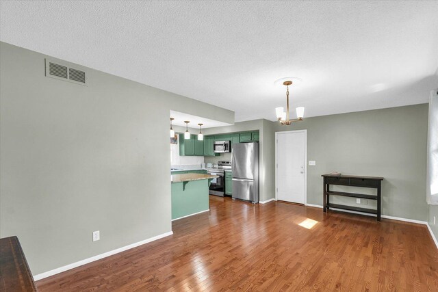 unfurnished living room featuring an inviting chandelier, dark hardwood / wood-style floors, and a textured ceiling